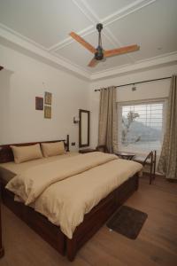 a bedroom with a large bed with a ceiling fan at Sanobar Home Stay in Bhīm Tāl
