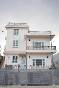 a white house with a fence in front of it at Sanobar Home Stay in Bhīm Tāl