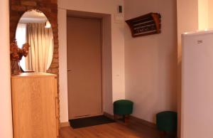 a hallway with a mirror and a door with two green stools at Cozy Alauksta apartment in Riga +2 photos