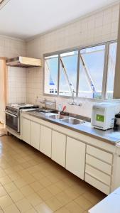 a kitchen with a sink and a microwave at Varanda do Mar Pitangueiras - 4 Quartos - Até 10 Pessoas - 2 Vagas in Guarujá