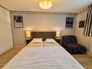 a bedroom with a large bed and a chair at Charmant logement de plain-pied avec Piscine in Loudenvielle