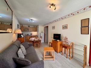 a living room with a gray couch and a kitchen at Charmant logement de plain-pied avec Piscine in Loudenvielle