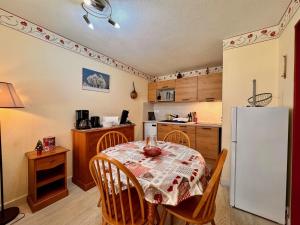a kitchen with a table and a white refrigerator at Charmant logement de plain-pied avec Piscine in Loudenvielle +5 photos