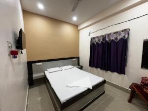 a bedroom with a bed and a curtain at Hotel Sundaram in Deoghar