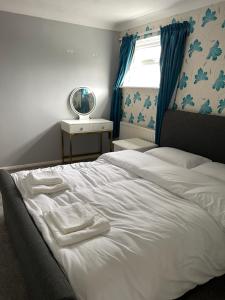 a bedroom with a white bed with towels on it at Selsey Home in Selsey