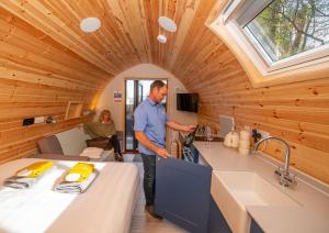 a man is standing in the kitchen of a tiny house at Beach House Pods in Dunoon