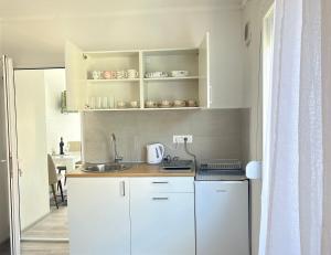 a small kitchen with white cabinets and a sink at White Rose 2 in Bar