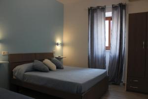 a bedroom with a bed with blue pillows and a window at B&B Raggi d'Ischia - nuova gestione 2026 in Casamicciola Terme +3 photos