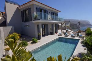 a villa with a swimming pool in front of a house at Villa Macedo in Ponta do Sol