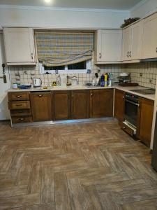 a kitchen with wooden cabinets and a wooden floor at Agios Stefanos TwoStory Maisonette in Néa Zoryiáni