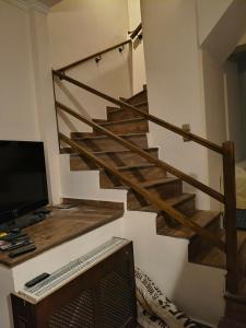 a living room with a staircase with a television and a television at Agios Stefanos TwoStory Maisonette in Néa Zoryiáni