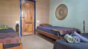 a bedroom with two beds and a wooden door at Emo Guesthouse in Kpandu
