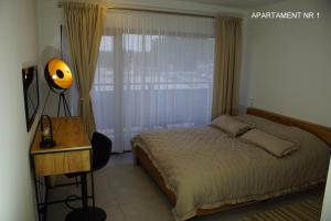 a bedroom with a bed and a desk and a window at Apartamenty ORION Trzęsacz in Trzęsacz