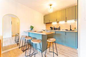 a kitchen with a blue island with stools at La bastide de Montech in Montech