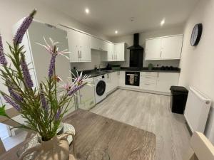 a kitchen with white cabinets and a table with purple flowers at Ridgeways Premium House in Bristol