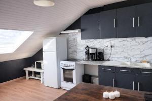 a kitchen with black cabinets and a white refrigerator at Le Petit Loft Vosgien -Escapade nature & cosy in Cornimont