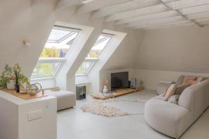 a white living room with a couch and a tv at CODAK suite in Kluisbergen