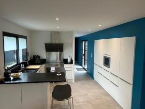 a kitchen with white cabinets and a blue wall at Villa d Architecte Moderne spa et piscine in Niort