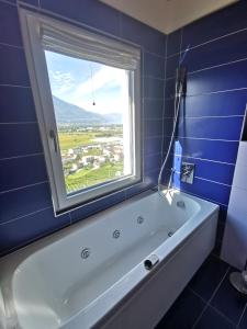 a bath tub in a blue bathroom with a window at Ca Mea - Lake View, Parking, EV in Gordola +10 photos