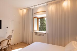 a bedroom with white curtains and a window at Terra d'Ombra Bed&Breakfast in San Gimignano