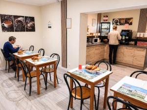 two people sitting at tables in a restaurant at Hôtel Le Petit Logis Chambres Confort climatisées in Beaumont-en-Véron