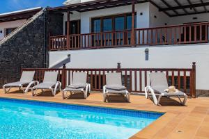 a swimming pool with chairs and a house at Villa Amana 5 star luxury resort for 10 people in Playa Blanca in Playa Blanca