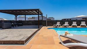 a swimming pool with lounge chairs and a patio at Villa Amana 5 star luxury resort for 10 people in Playa Blanca in Playa Blanca