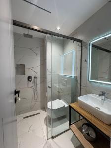 a bathroom with a glass shower and a sink at Alesia's Guesthouse in Vlorë +81 photos
