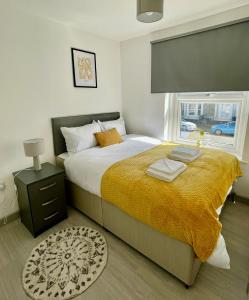 a bedroom with a large bed with a yellow blanket at Ridgeways Premium House in Bristol