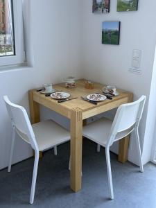 a wooden table with chairs and plates and bowls on it at Studio mit Alpenblick und privaten Terrasse in Kleinweil +4 photos