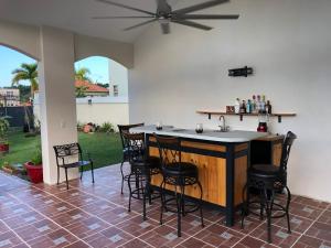 a patio with a bar with chairs and a ceiling fan at A Private Paradise by the Rainforest in Luquillo