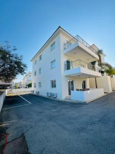 a large white building with a parking lot at Amigos Apartment Mythical in Protaras