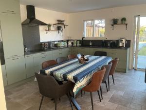 a kitchen with a table with chairs and a kitchen with a counter at Maison de vacances Helios in Seignosse