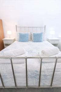 a bed with white sheets and blue pillows on it at Angel Lane Alnwick Apartment in Alnwick +2 photos