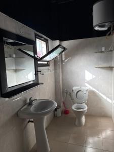 a bathroom with a toilet and a sink and a window at Chez Sira in Warang