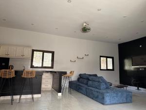 a living room with a blue couch and a kitchen at Chez Sira in Warang