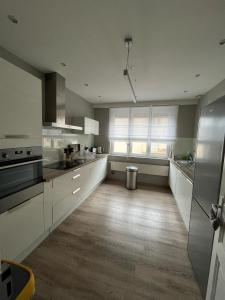 a large kitchen with white cabinets and a wooden floor at L'Ourson in Colmar