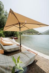 two beds and an umbrella next to a lake at koman_lakeview_apartments in Shkodër