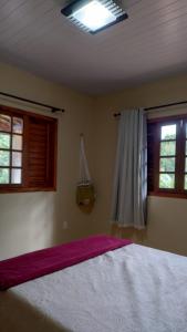 a bedroom with a large bed and two windows at Recanto da Julie in Mulungu