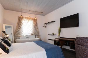 a bedroom with a bed and a tub and a television at Pjazza Suites Boutique Hotel by CX Collection in Siġġiewi