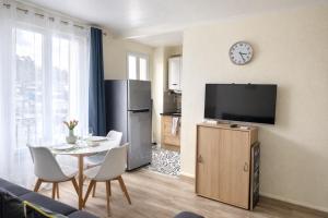 a living room with a table and a clock on the wall at T2 cosy & calme - Gare à 1 min accès direct Paris & CDG in Aulnay-sous-Bois
