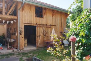 a wooden barn with a door and a table at Les Jardins de Colmar in Herrlisheim-près-Colmar
