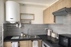 a kitchen with a sink and a microwave at T2 cosy & calme - Gare à 1 min accès direct Paris & CDG in Aulnay-sous-Bois +9 photos