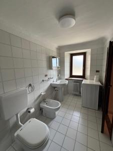 a white bathroom with a toilet and a sink at Casa parrocchiale La Salle in La Salle