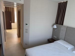 a bedroom with a white bed and a hallway at Hotel Porto Azzurro in Sirmione