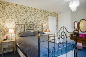 a bedroom with a bed and a wall with floral wallpaper at Lee's Historic Mansion in Cheshunt