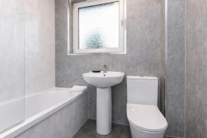 a bathroom with a sink and a toilet and a window at Celtic City Stay in Glasgow