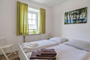 a white bedroom with two beds and a window at Knusthof Lafrenz - Küstenblick in Fehmarn
