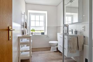 a white bathroom with a toilet and a window at Knusthof Lafrenz - Küstenblick in Fehmarn