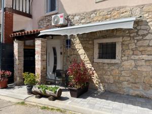 a stone house with an awning and a patio at Apartman Lari in Vižinada